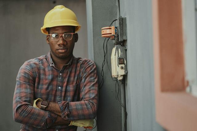 Tradesperson wearing a hard hat and safety glasses with arms folded